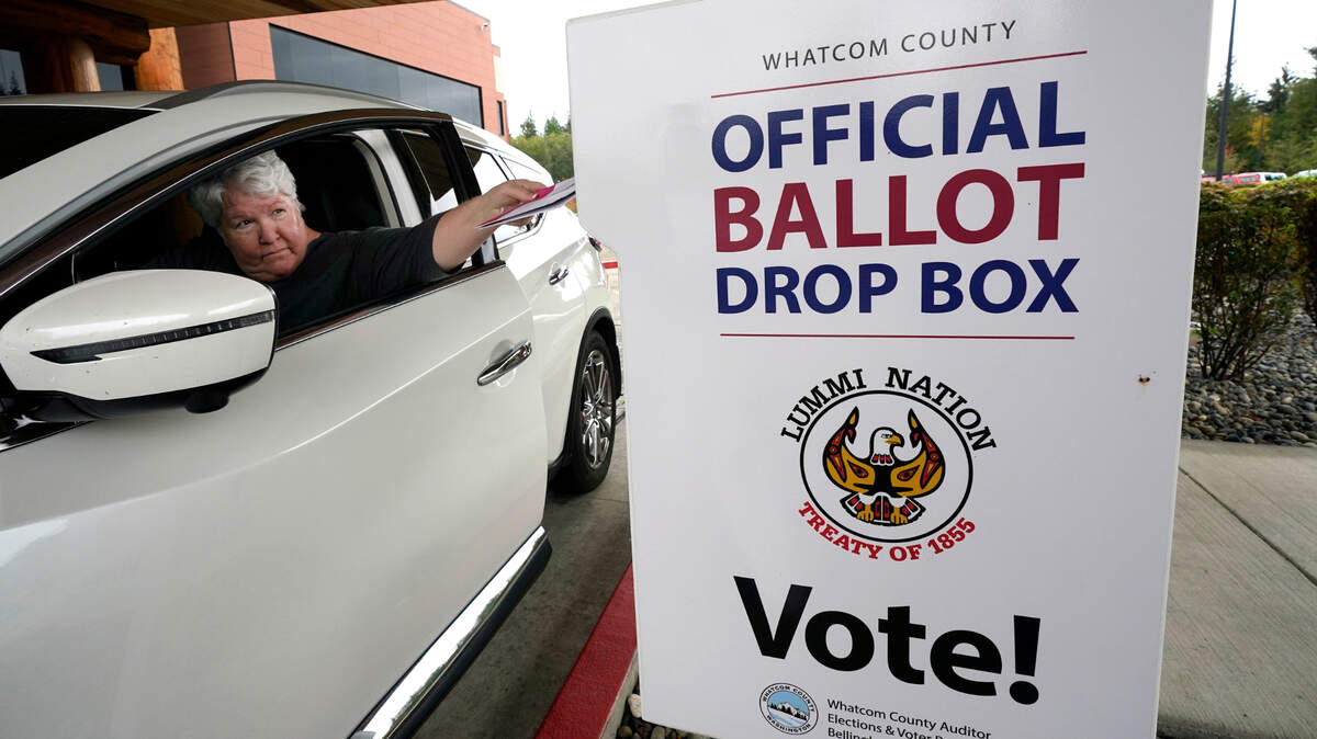 Lesley Beckley drops her completed ballot into a ballot drop box Monday, Oct. 19, 2020, on the Lummi Reservation, near Bellingham, Wash. Washington state is one of five states, along with Colorado, Hawaii, Oregon, and Utah, that conduct election entirely by mail-in voting.