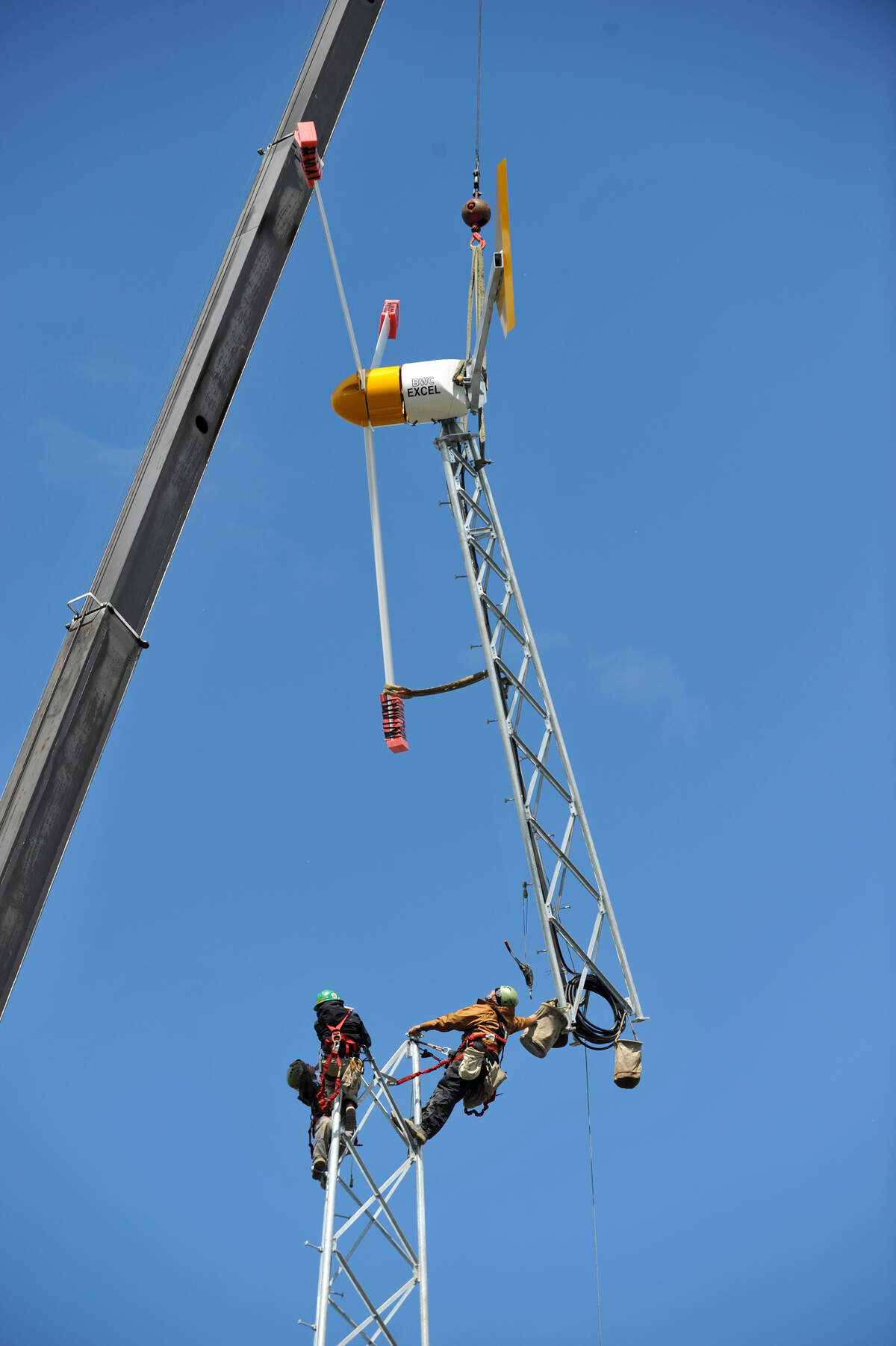 Technicians install top section of a 7.5kW wind turbine into place at Alpha Technologies, Inc, in Bellingham in 2010. The wind tower, solar array and generator showcase multiple renewable energy sources for remote communications systems.