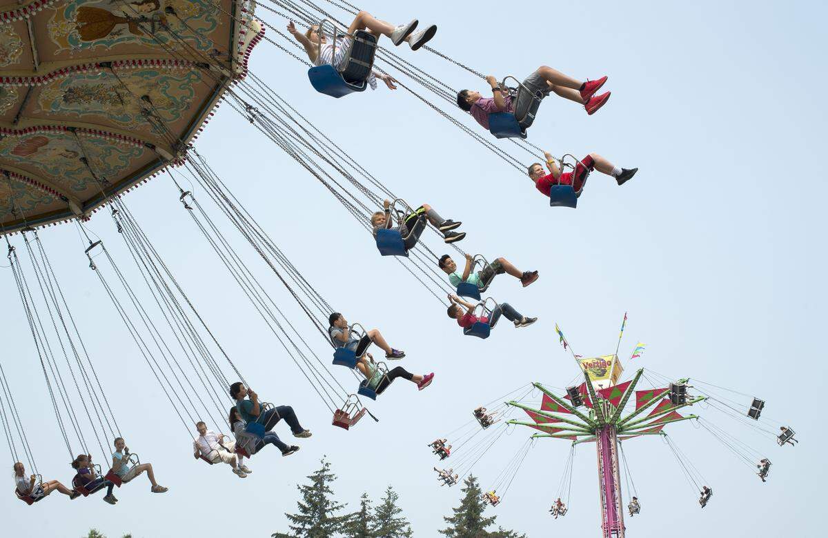 Fairgoers ride the Wave Swinger, left, and the Vertigo at the Northwest Washington Fair on Tuesday in Lynden.