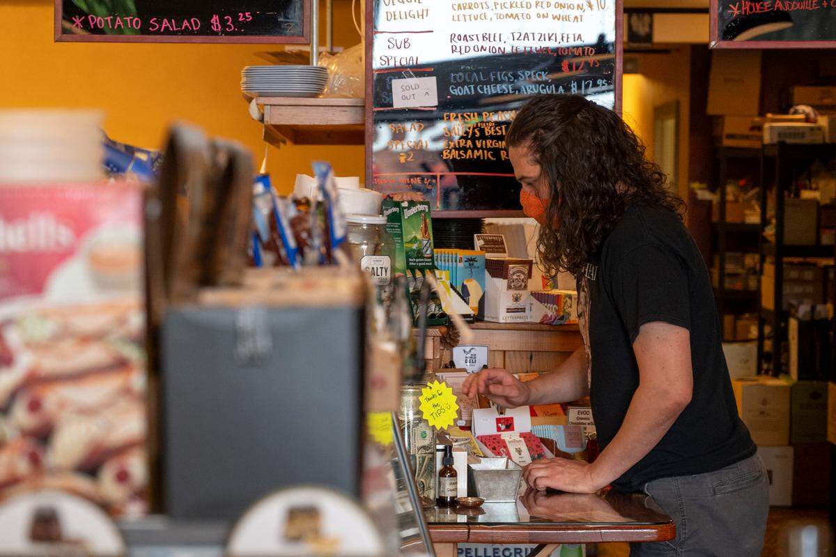 A customer pays for his meal while wearing a mask to prevent the spread of COVID-19 at Old World Deli on Wednesday, Aug. 15, in Bellingham.