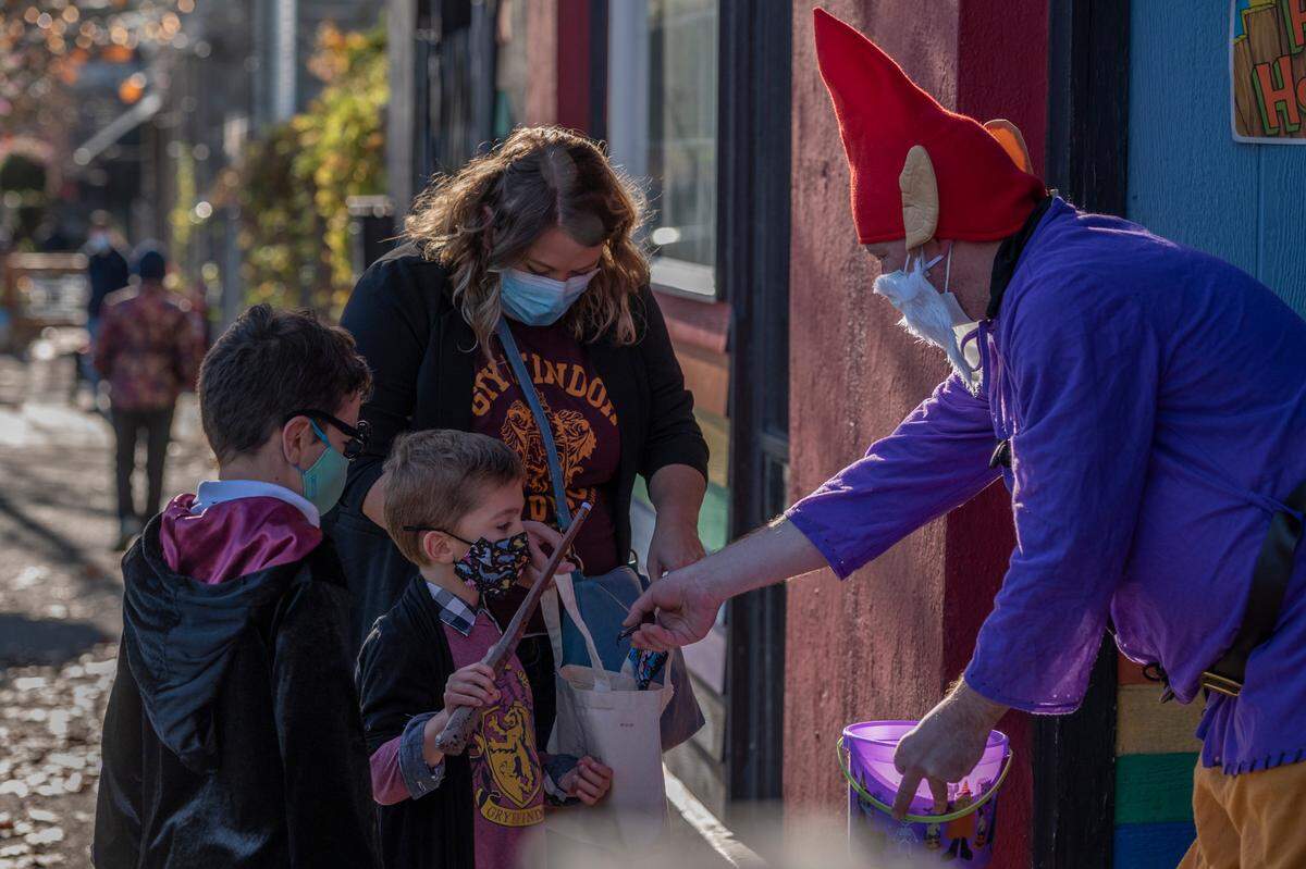 Children dressed in their Halloween costumes receive candy from Bellingham businesses in 2021.