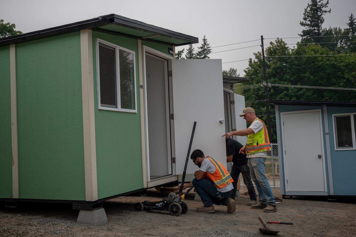 Crews from the city of Bellingham level new tiny homes at the Gardenview Village on the corner of Lakeway Avenue and Woburn Street on Friday, Aug. 13, 2021, in Bellingham, Wash.