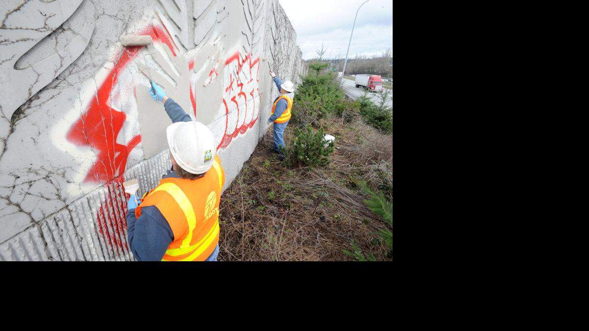 Washington State Department of Transportation employees Stan Hanson, Maintainence Lead Tech, left, and Dale McClellan, Maintainence Tech 2, cover up graffitti Monday morning, January 25, 2011 that was spraypainted the night before on the southbound Interstate 5 soundwall just north of the Lakeway exit. "When graffitti happens we want to cover it up as soon as possible, especially if there's profanity," said Hanson.