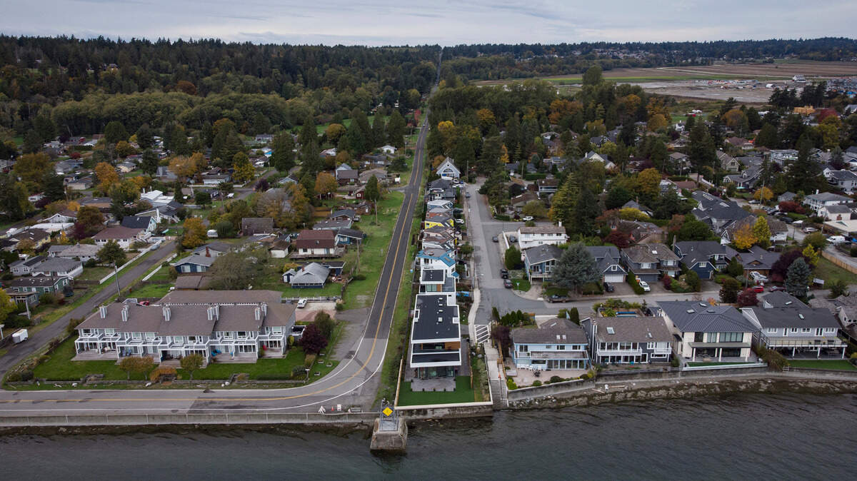 Homes in Delta, British Columbia, left, and Point Roberts, Wash., right, are separated by the Canada-U.S. border that is just north of Roosevelt Way in Point Roberts, as seen in an aerial view on Wednesday, Oct. 13. Point Roberts sits on a peninsula and is only accessible by land by traveling through Canada. Beleaguered business owners and families separated by COVID-19 restrictions rejoiced after the U.S. said it will reopen its land borders to nonessential travel Nov. 8, ending a 20-month freeze.