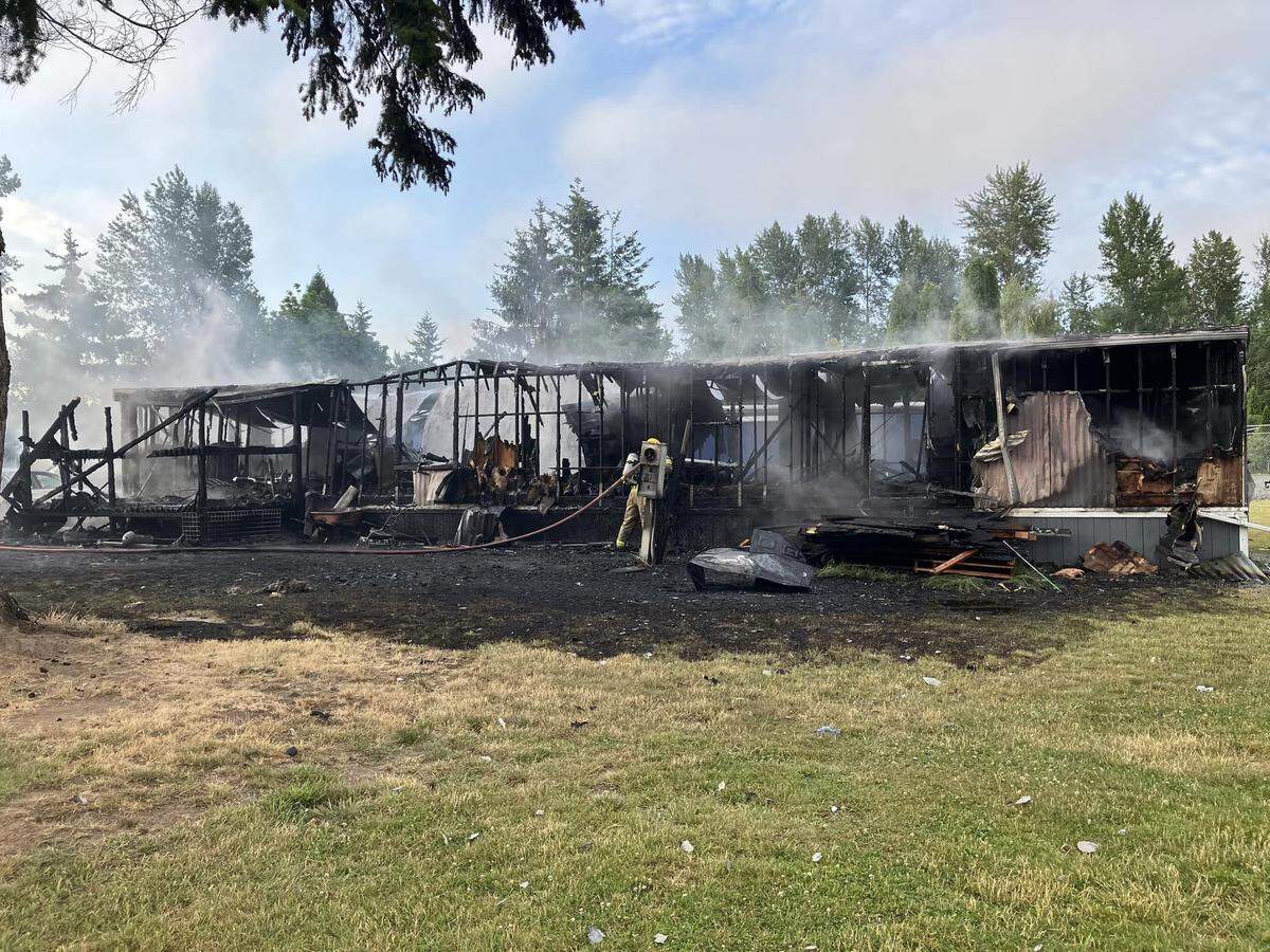 A Bellingham Fire Department firefighter works to extinguish a mobile home fire on June 25, 2023, at the Bakerview Estates mobile home community in Bellingham, Wash.