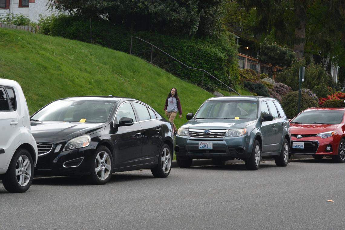 A person walks past cars with parking tickets on North Garden Street near Oak Street near the Western Washington University campus in Bellingham, Wash., on Friday, May 13, 2022.