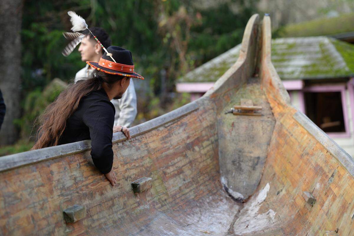 Raven Borsey feels the side of a canoe he plans to refurbish with his brother as part of an effort to revitalize the Lummi Youth Canoe Family on November 22, 2024, on the Lummi Reservation.