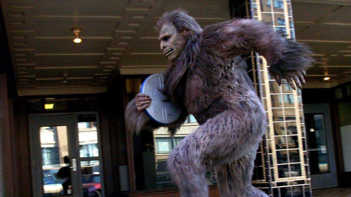 An image of a man in a Bigfoot costume running down a street.