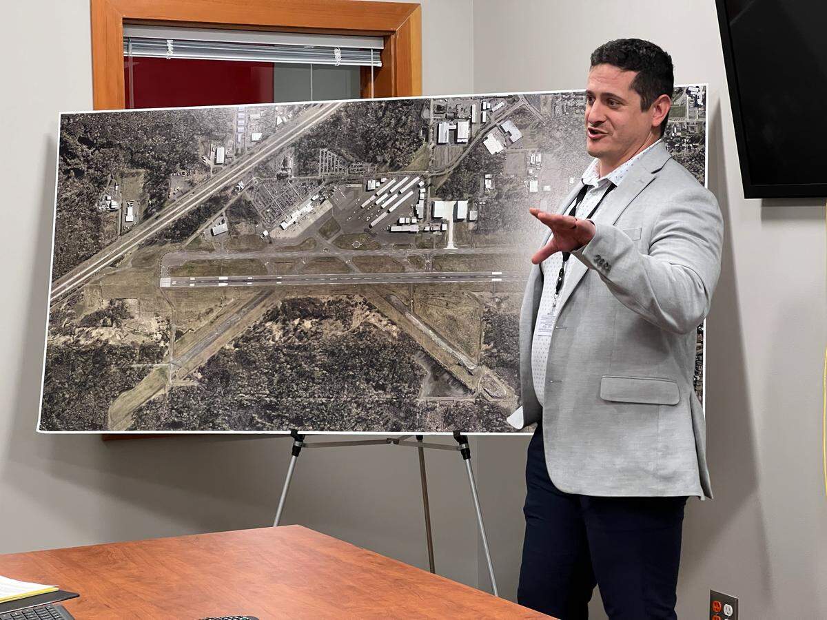 Matthew Rodriguez, director of aviation at Bellingham International Airport, discusses airport runway rehabilitation plans with an aerial photo of the airport on Tuesday in the airport administrative offices.