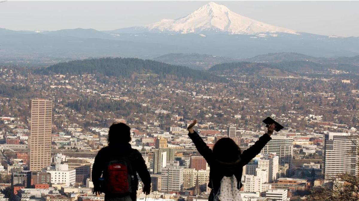 A young couple enjoys the view of Mount Hood looming over downtown on a spring-like day in Portland, Ore.