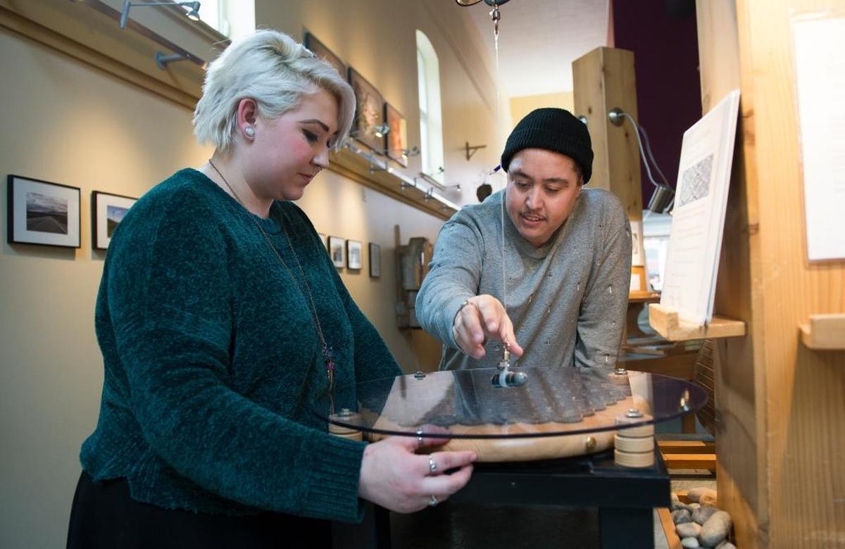 Hayley Weatherstone, left, and Chris Vargas play with 100 compasses using a magnet at Mindport Exhibits Feb. 8 in Bellingham.