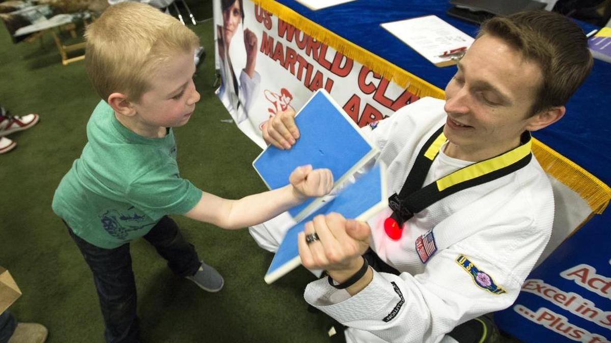 Aiden Anson, 6, breaks a board held by Michael Boyce, right, at the USTA Martial Arts booth during the Bham Fam Fair on March 28, 2016, at the Sportsplex in Bellingham.