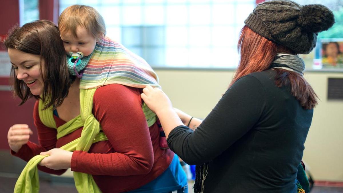 
Participants at a Bellingham Babywearers event in 2014 at Bellingham Public Library try wraps and help other mothers secure their babies.

