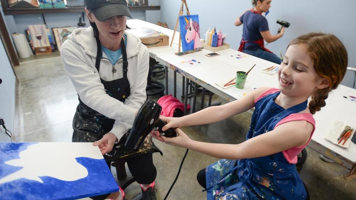 Karen Andrews and her daughter Kaitlyn Andrews, 8, dry a portrait of a unicorn at the new location of Uptown Art studio at 800 Harris Ave., No. 101 in the Fairhaven District of Bellingham, Thursday, April 13.