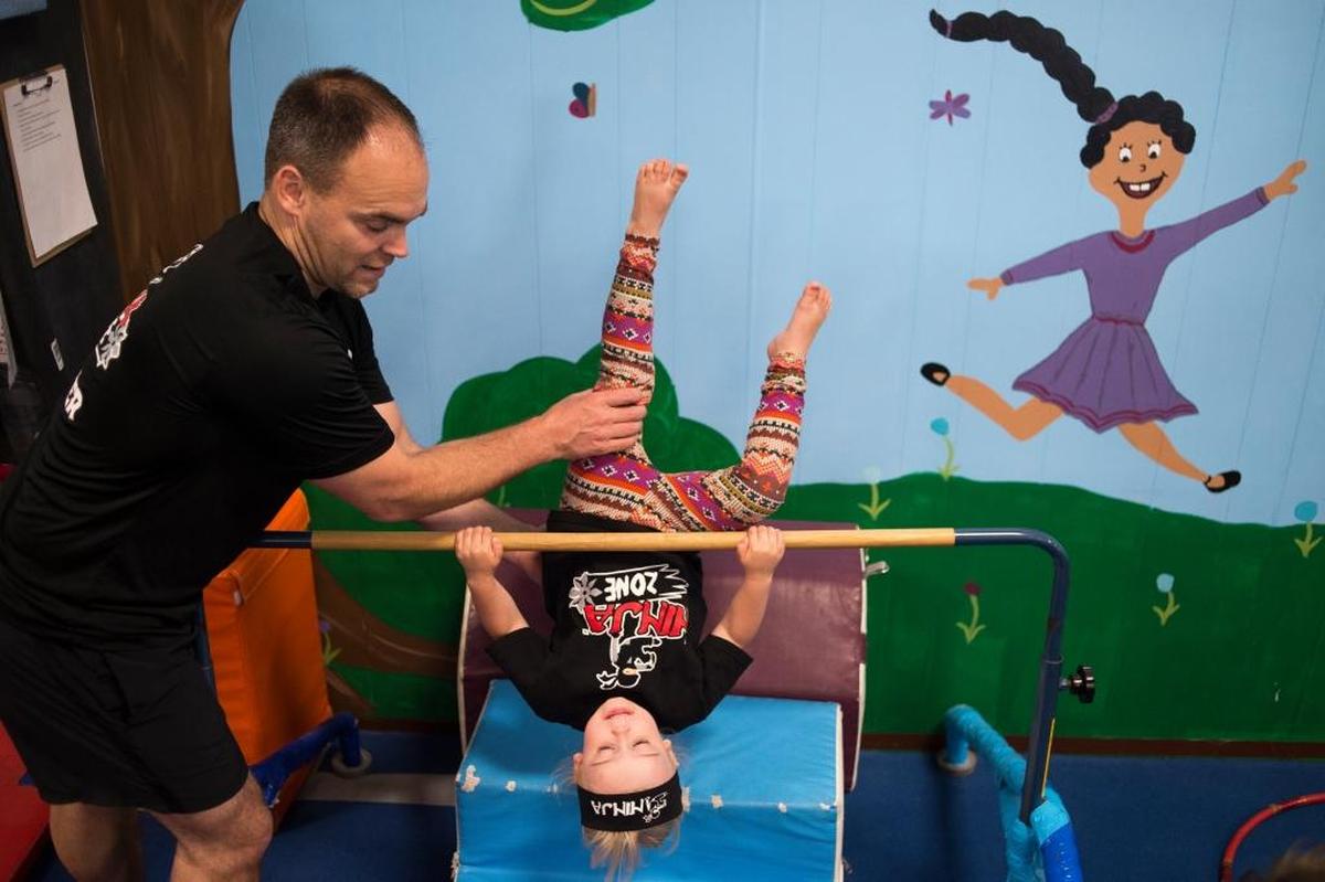 Kent Charette, co-owner of North Coast Gymnastics Academy, helps a Ninja Zone student through an obstacle on Friday, June 23, in Bellingham.