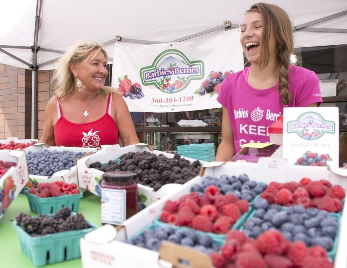 Barb Kraght, left, and Kiya Levin, right, of Barbie’s Berries laugh and talk with customers at the 2014 Northwest Raspberry Festival.