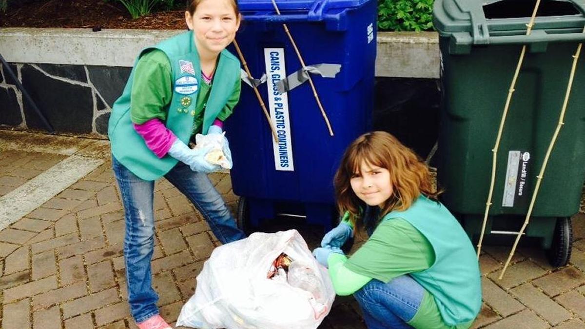 Junior Girl Scouts help with the trash and recycling at a community event.