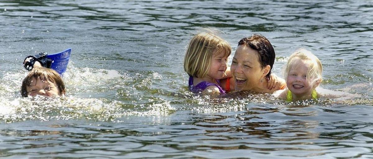 Kyler Southcott, left, splashes with his flippers as friends Lauren Meucci and Lizzie Fiesen, far right, then 5, go for a refreshing dip with his mother, Bonnie Hart Southcott, at Lake Padden in June 2003.