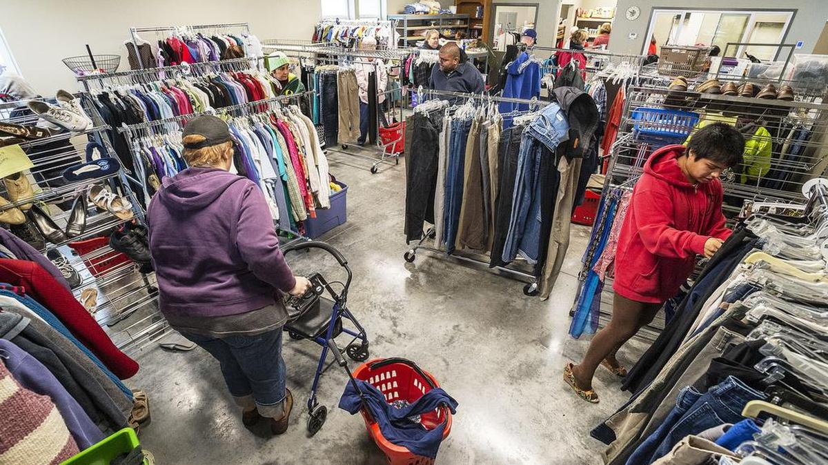 Clients look through the clothing racks at Hope House during opening day of its new facility behind the Church of the Assumption in Bellingham. It distributes clothing, baby supplies and household items.