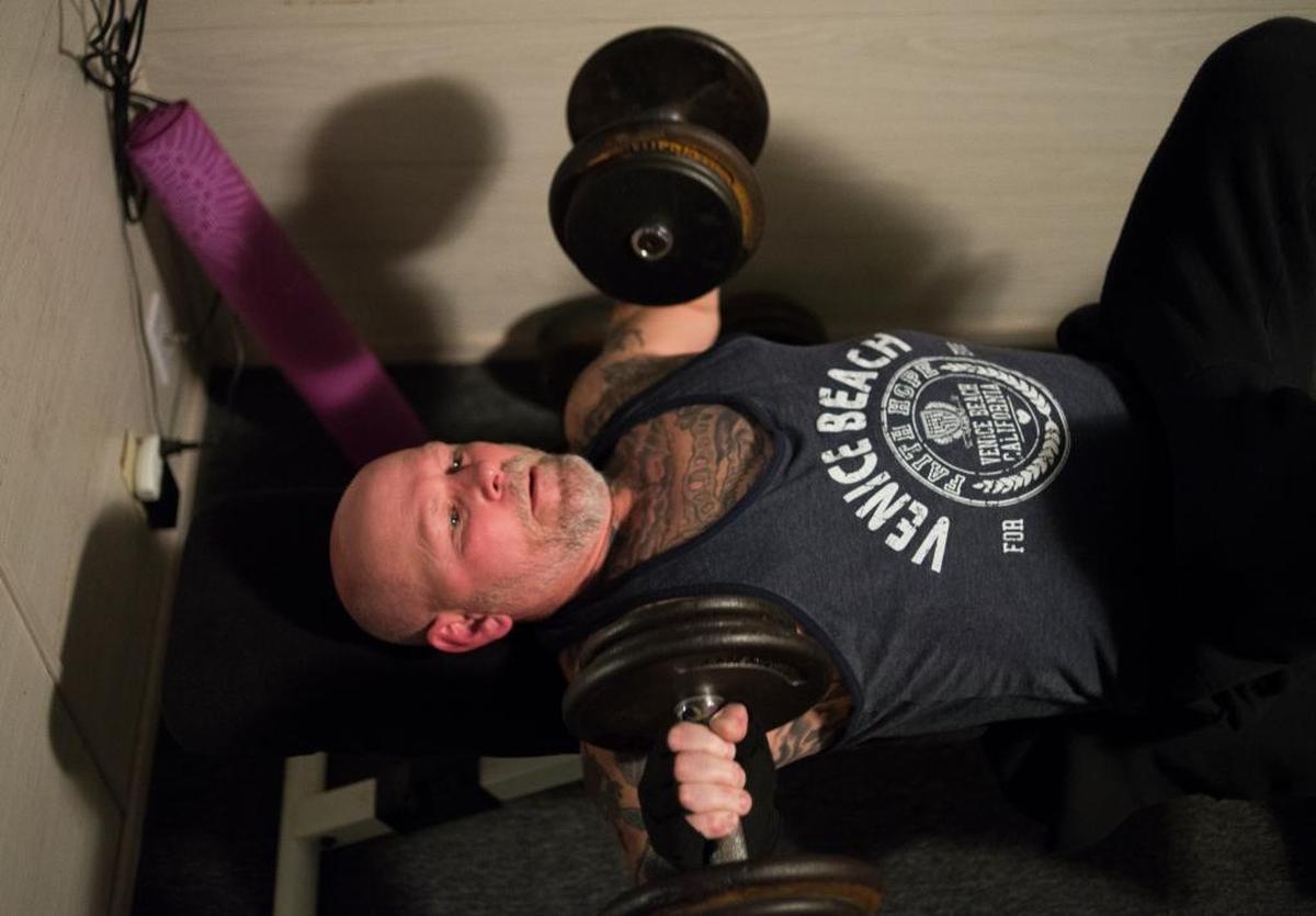 Scott Ranahan bench presses dumbbells while working out March 29 in Bellingham. Ranahan, who had to learn how to walk again after being hospitalized with the flu, lives with post-intensive care syndrome and works out twice a day to build and maintain his ability to move.