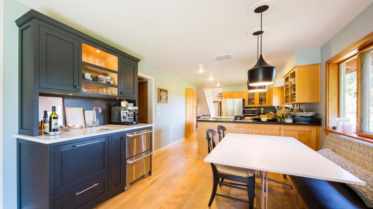 The kitchen space at the rear was already part of the Treat family house, but the foreground is a new extension. What appears to be a hutch, at left, is a built-in unit with a small beverage refrigerator, a dishwasher hidden behind a wooden front, and a small bar sink.