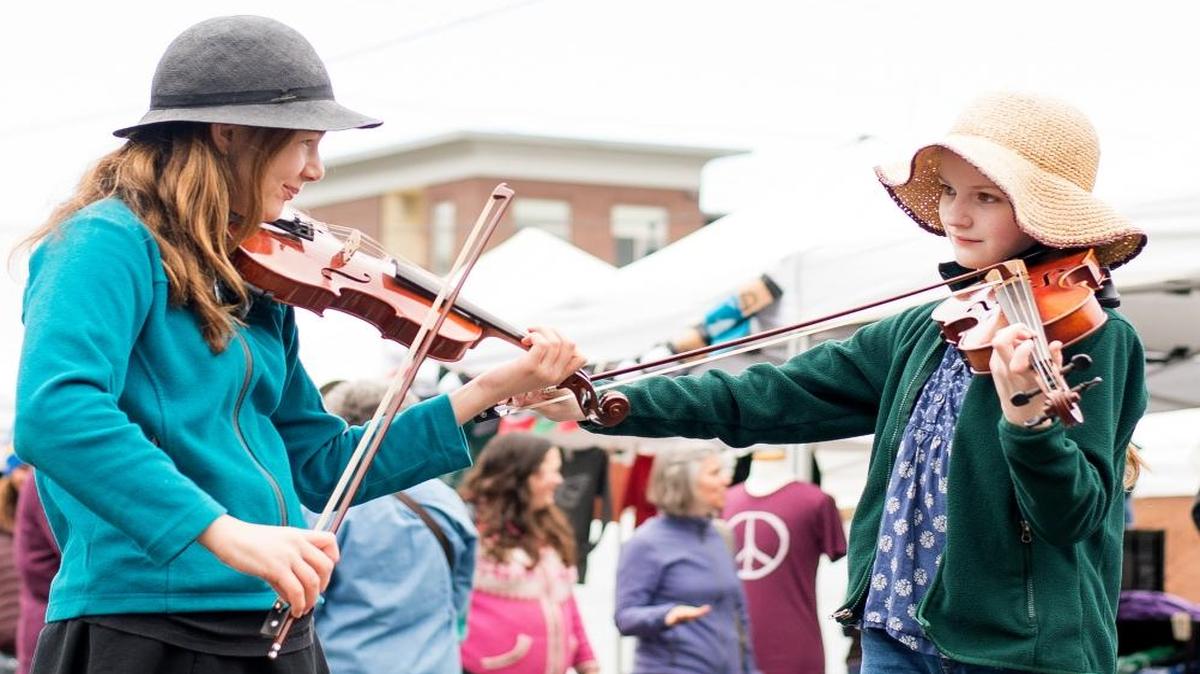 Paige Graham, 12, left, and Anna Sophia Flanagan, 11, play violins at Bellingham Farmers Market on the market’s opening day, April 2, 2016, at Depot Market Square.