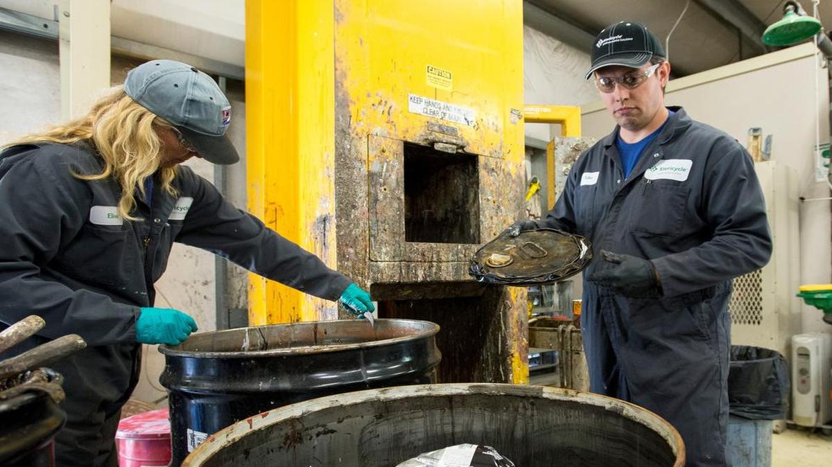 
Alice Cords, left, cleans the seal of a barrel containing waste paint while Tyler Eaton looks to dispose a crushed paint can in July 2015 at the Disposal of Toxics Facility in Bellingham.
