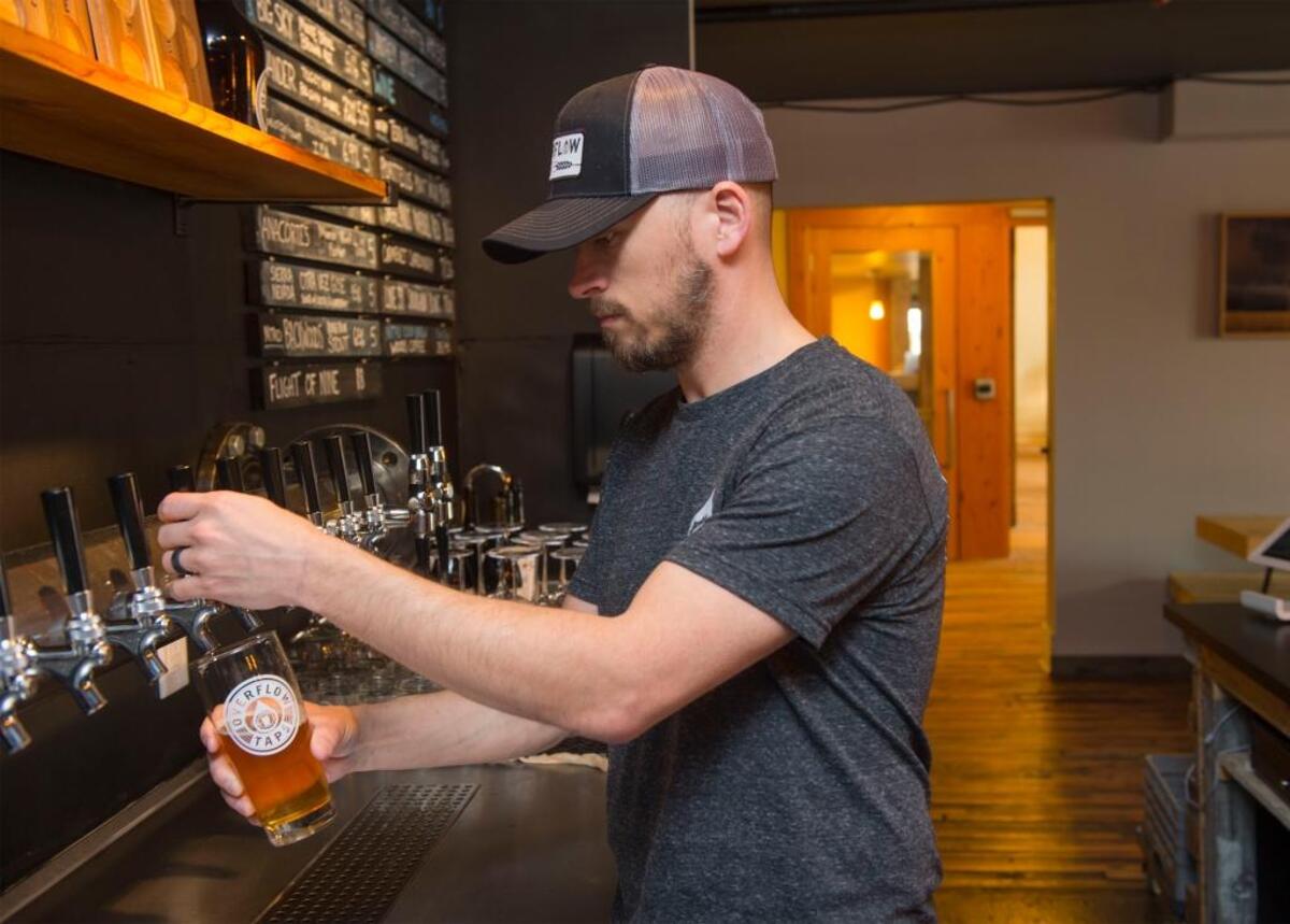 Co-owner Jesse Nelson pours a beer at Overflow Taps, inside the Waples Mercantile Building on Front Street in Lynden, on April 11, 2016.
