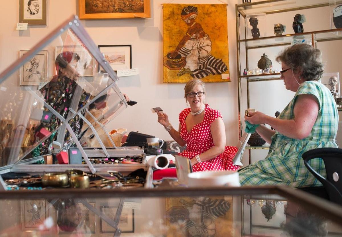 Franny Erickson, center, discusses an item with Lisa Distler, right, while helping a customer at an estate sale put on by EarthaKittys in Bellingham.