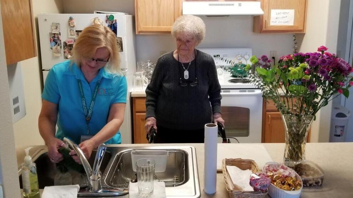 Right at Home Certified Nursing Assistant Jeni Bliss-Vinson washes dishes while visiting Velma MacDonald, 93, at her apartment at Spring Creek by Bonaventure in Bellingham. Bliss-Vinson visits twice a week to help with showering and housework.