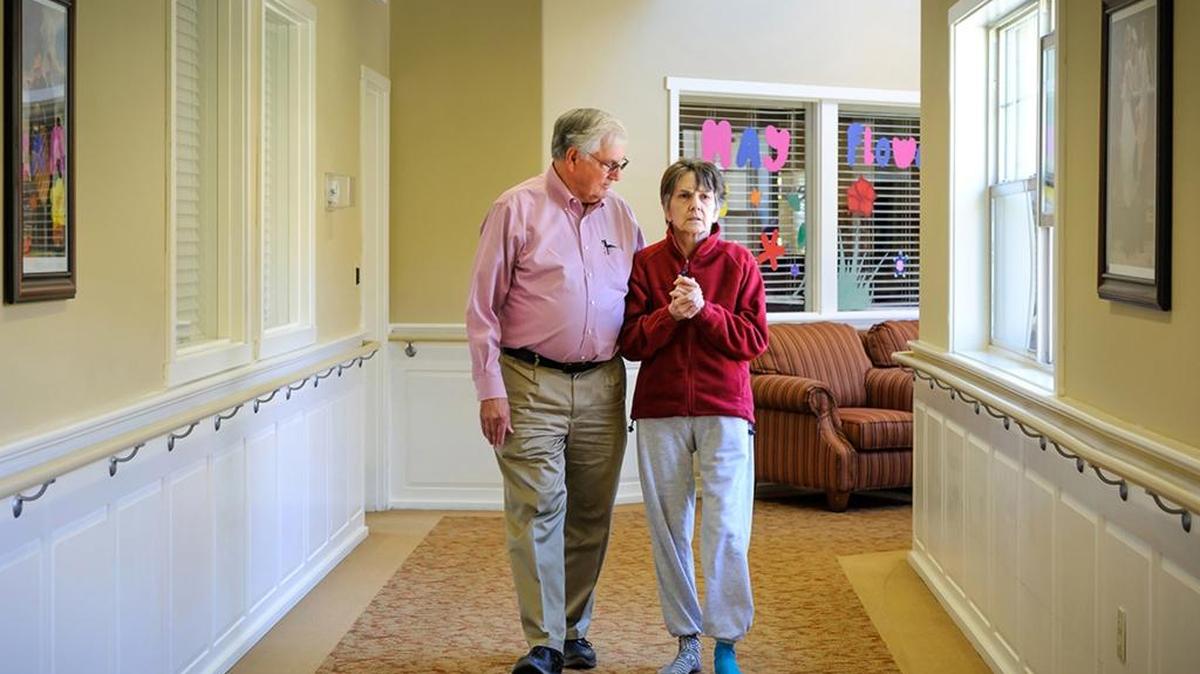 Bill Harris walks with his wife, Nora, at the Fern Gardens memory care center in Medford, Ore. Nora Harris, 64, has late-stage Alzheimer’s disease. A former librarian and world traveler, she had signed an advance directive stipulating no care to prolong her life. Controversy has arisen over her husband’s claim that state law is forcing her to be spoon-fed against her stated wishes.