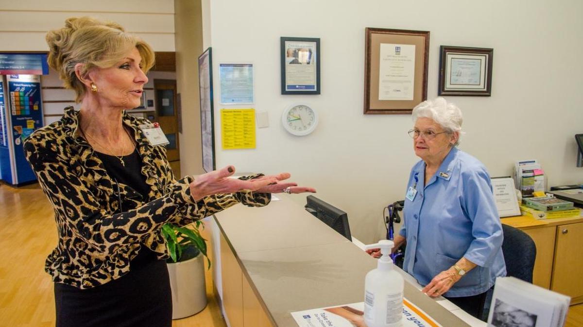 Marci Scott, director of the volunteer program at PeaceHealth St. Joseph Medical Center, talks with Monta Wagar, a volunteer at the main lobby information desk, March 17, 2016, at the hospital.