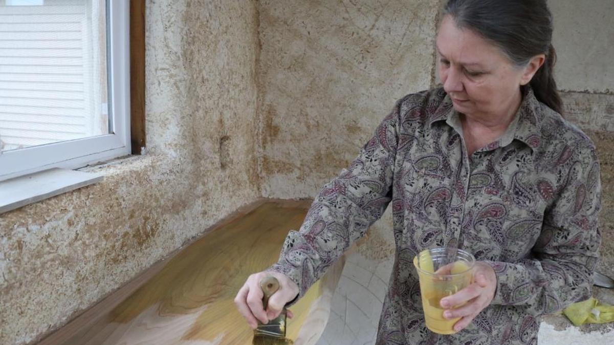 Pam Bosch of Bellingham applies Hemp Shield, a hemp-oil wood sealer, to a window ledge inside a small demonstration building on her property that’s made with hemp hurd and lime.