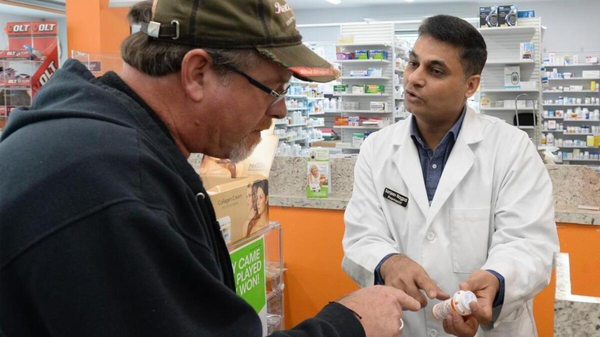 Pharmacist Sanjeev Nagpal talks to customer Mark Lau at Rx Mart Pharmacy in Bellingham on April 20.