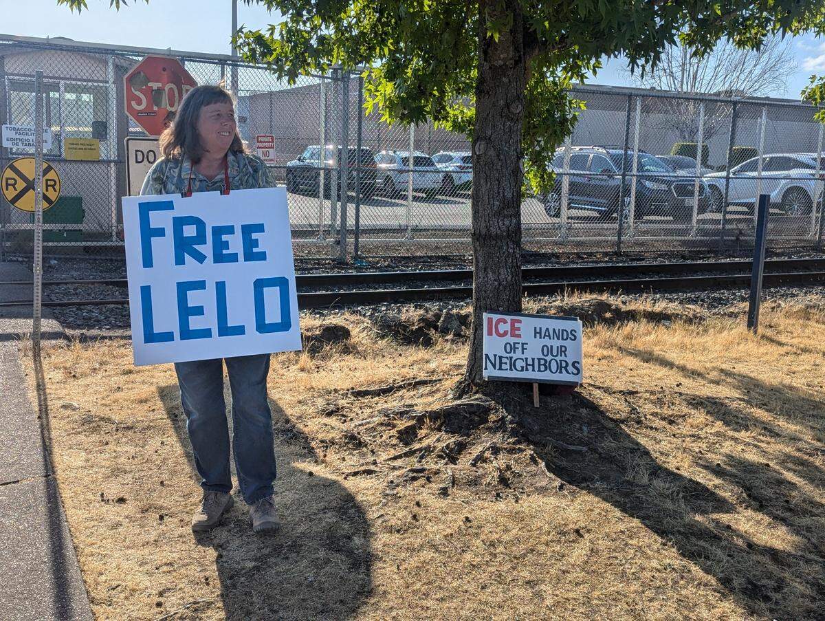 A woman holds a “Free Lelo” sign outside the Tacoma Northwest Detention Center on July 14, 2025. Whatcom County farmworker and labor activist Alfredo “Lelo” Juarez Zeferino requested voluntary departure during a hearing the same day, and a judge granted the request.