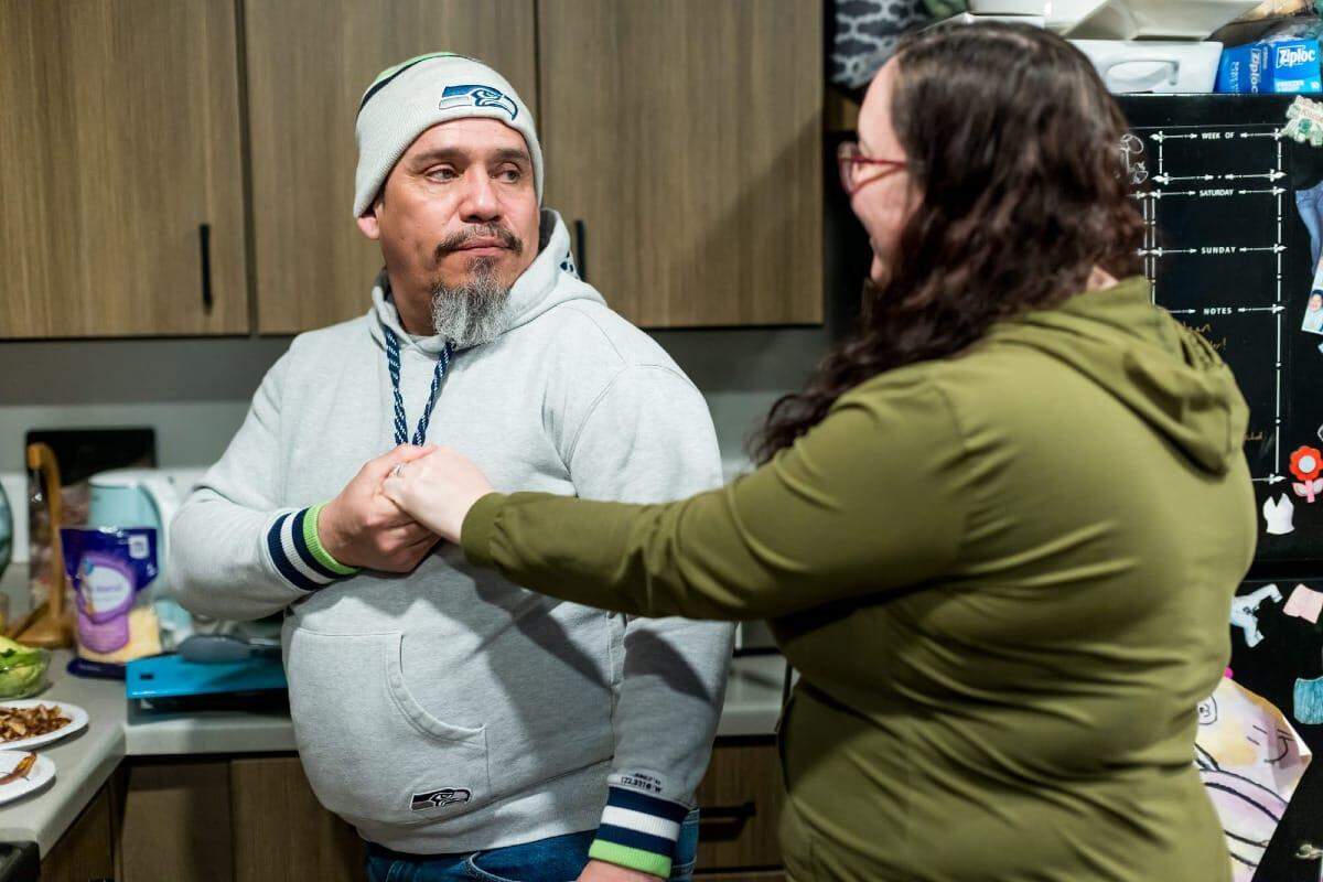 Wilfredo Castillo and his wife, Karri, share a moment while preparing dinner at the home in Mill Creek, Wash.