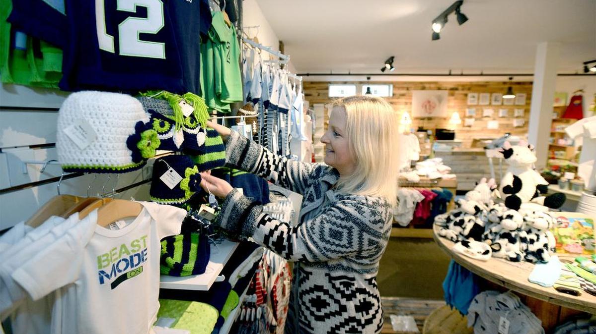 Shelly Allen straightens up her collection of Seahawks clothing at the second location of Bellingham Baby Co., in the Waples Mercantile Building on Front Street in Lynden on Monday, Jan. 11. The store sells custom-made gifts for newborns to toddlers. The company’s first store is located in Barkley Village in Bellingham.