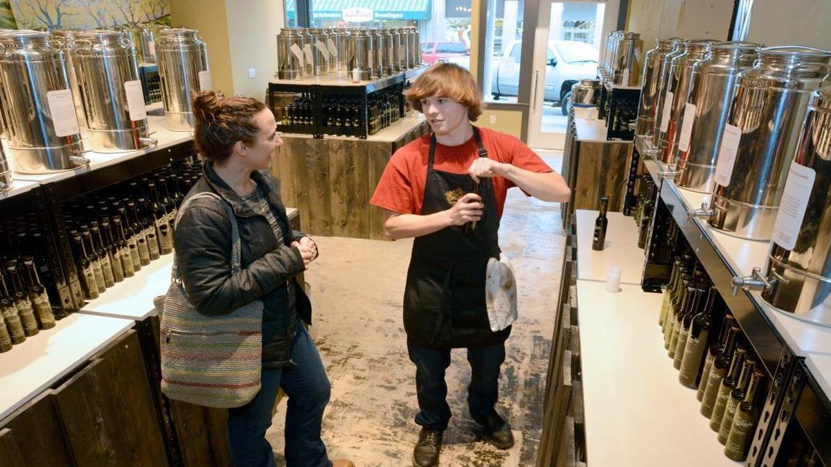 Customer Christie Dukue, is helped by Austin Bach at the new Drizzle tasting room in the Waples Mercantile Building in Lynden on Dec. 17, 2015. The store opened Dec. 14 and sells premium olive oils, vinegars, spices and salts. It also has a small cafe.
