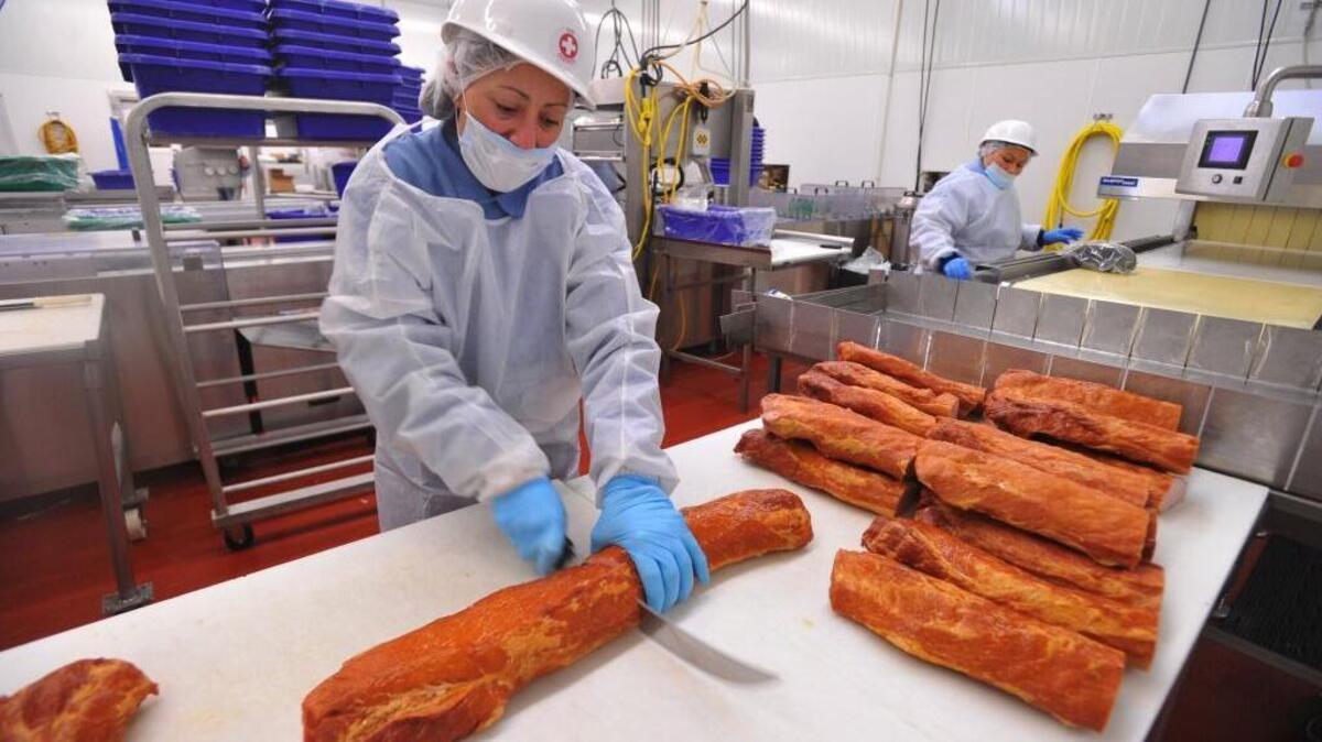 Argelis Quintanar, left, cuts Canadian bacon into 5-pound halves as she and other workers package the meat at Hempler Foods Group Wednesday April 20, 2011 in Ferndale.The company has acquired another Washington firm, Fletcher’s Fine Foods, in a deal worth about $5 million.