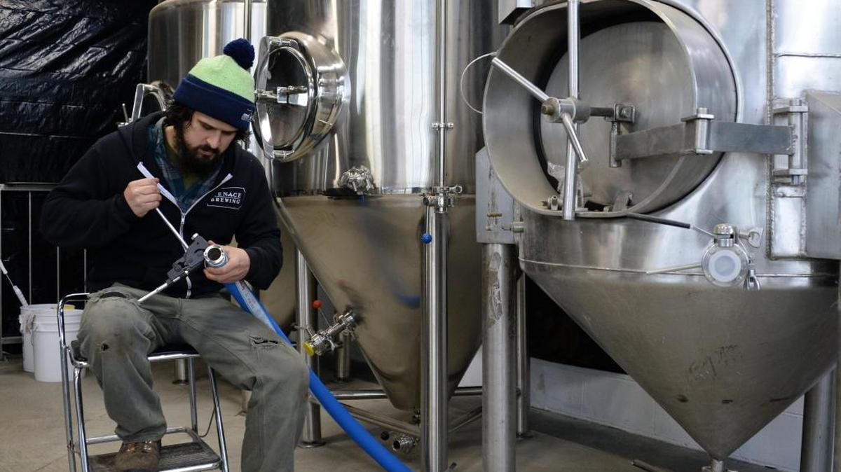 Menace Brewing co-owner Ben Buccarelli works on a hose fitting while setting up the brewery at its new location on Meridian Street in Bellingham Friday, Dec. 2, 2016. The new Fountain District brewery and tap room should be open by the end of December.