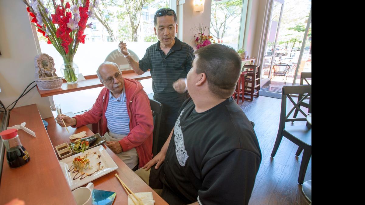 
Owner Jun Bark, center, serves up sushi to customers Adib Jamshedi, left, and Victor Johnson at the new Jun’s Sushi & Bento restaurant on Railroad Avenue in Bellingham on June 9.
