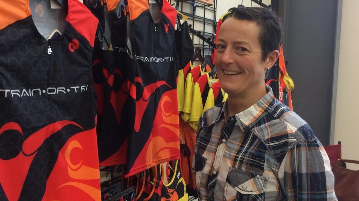 Maureen “Mo” Trainor stands next to her own clothing line at her Train or Tri store at 909 Squalicum Parkway on Wednesday, Dec. 3. Trainor recently opened the business, which offers products for triathletes and cyclists.