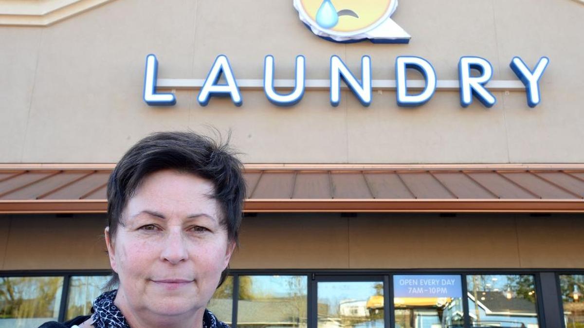Q Laundry owner Colleen Unema stands Tuesday, Feb. 23, in front of her Bellingham business, which she is renaming Brio Laundry to avoid fighting another business for the Q Laundry name. Unema covered the Q logo with a crying emoticon while she waits for the new signs.