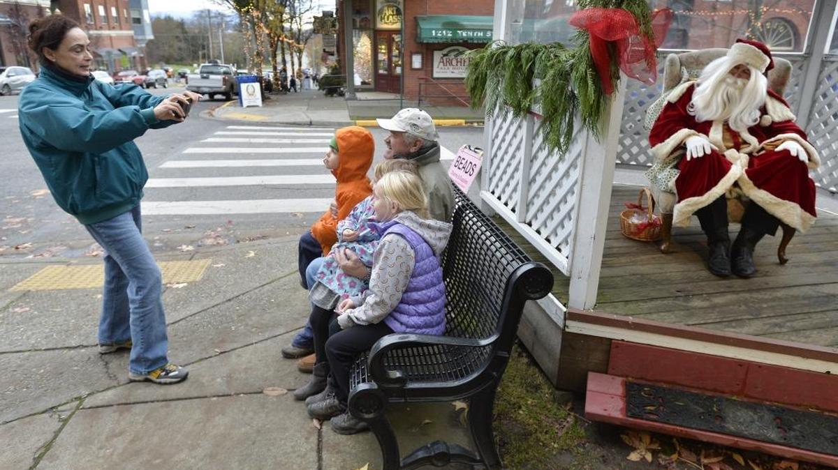Elena Cardinal, left, visiting from Vancouver, Wash., takes a photo of her grandchildren Canyon Cardinal, 5, Bronwyn Hicks, 6 and Iris Hicks, 10, with her husband Don Cardinal, while Santa waits to have his picture taken during the annual Fairhaven Holiday Festival on Nov. 28, 2014. This year’s event is Nov. 27-28 and includes a visit from Santa, free carriage rides and a holiday art walk.