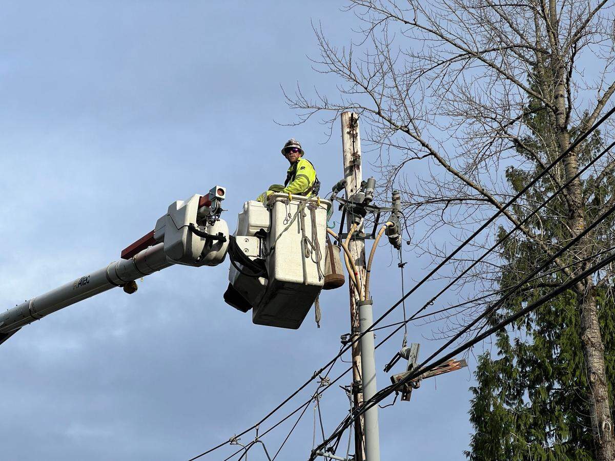 A utility worker from Asplundh repairs a Puget Sound Energy power pole that was damaged in the bomb cyclone storm on Wednesday.