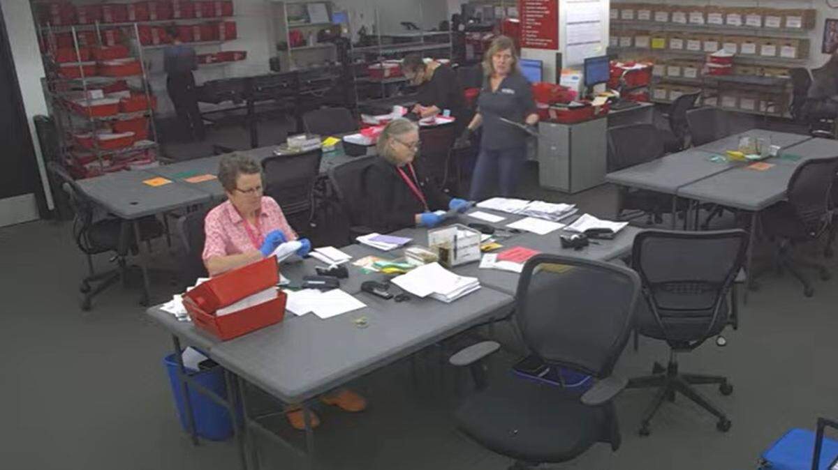In a screenshot from a webcam in the Whatcom County Auditor’s Office Elections Division, poll workers examine ballot envelopes for voter signatures and then open the envelopes on Wednesday in the basement of the County Courthouse in Bellingham.