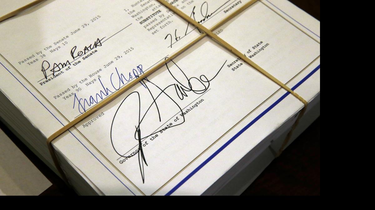 
The two-year state operating budget for Washington state is shown after it was signed by Washington Gov. Jay Inslee, lower right, House Speaker Frank Chopp, and Senate president Pam Roach late on June 30, at the Capitol in Olympia. Included in the budget are cuts in tuition for college students that have triggered a new look at the state’s Guaranteed Education Tuition program.
