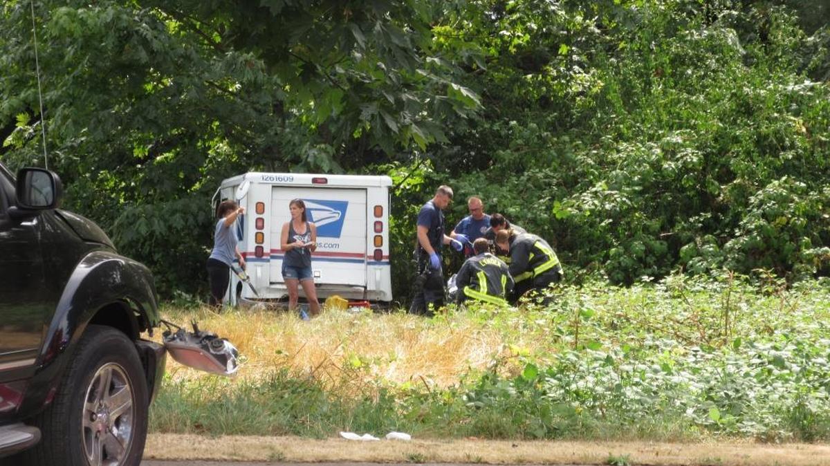 Lynden firefighters treat the injured postal worker near his truck, called an LLV, at the corner of South Garden and Grover streets east of downtown Lynden on Wednesday, Aug. 23.