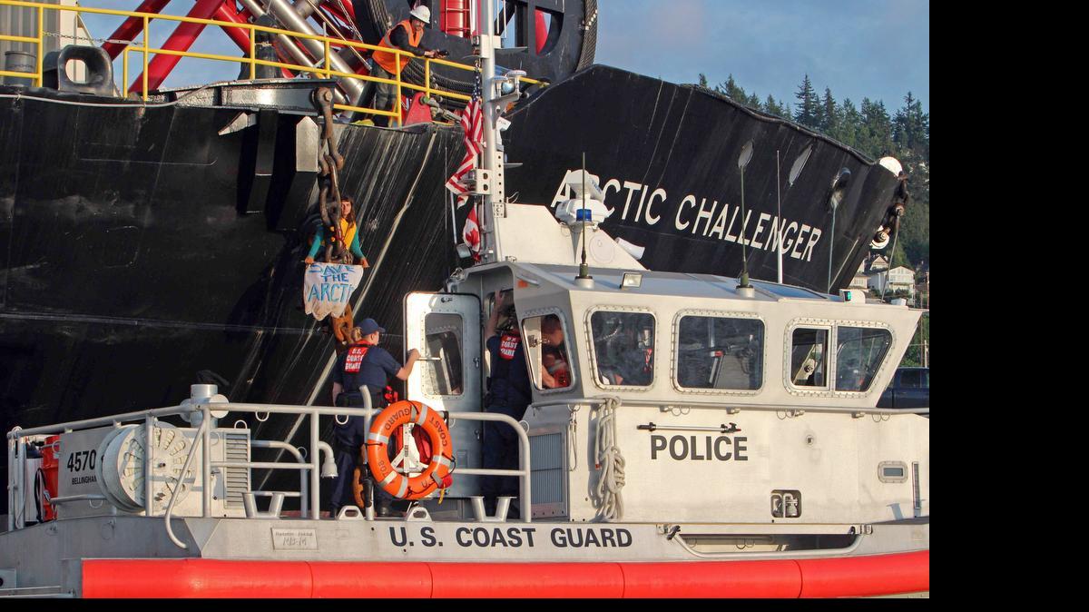 
In this Friday, May 22, 2015 photo provided by Reese Semanko, the Coast Guard stands by as a woman identified as Chiara D’Angelo has suspended herself in a climbing harness from the anchor chain of the Royal Dutch Shell support ship Arctic Challenger in the harbor at Bellingham, Wash.

