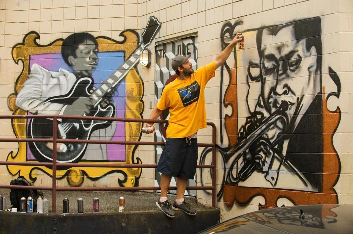 Shawn Cass adds Miles Davis to a mural of blues, soul, r&b and funk musicians on the alley side of Tha Outlet on Wednesday, Sept. 6, in Bellingham.